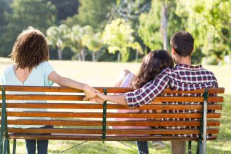 Lonely woman sitting with couple in park